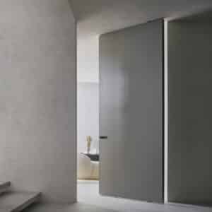 Rimadesio Radius taatsdeur in gelakt glas, toegepast als architectonisch binnendeursysteem in een entreehal met zichtlijn naar de living