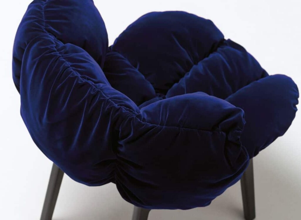 Close-up van de diepe, gewatteerde fluwelen bekleding van de Blue Velvet stoel. De verfijnde textuur en rijke kleur benadrukken het luxe karakter van deze stoel, ontworpen door Edra.