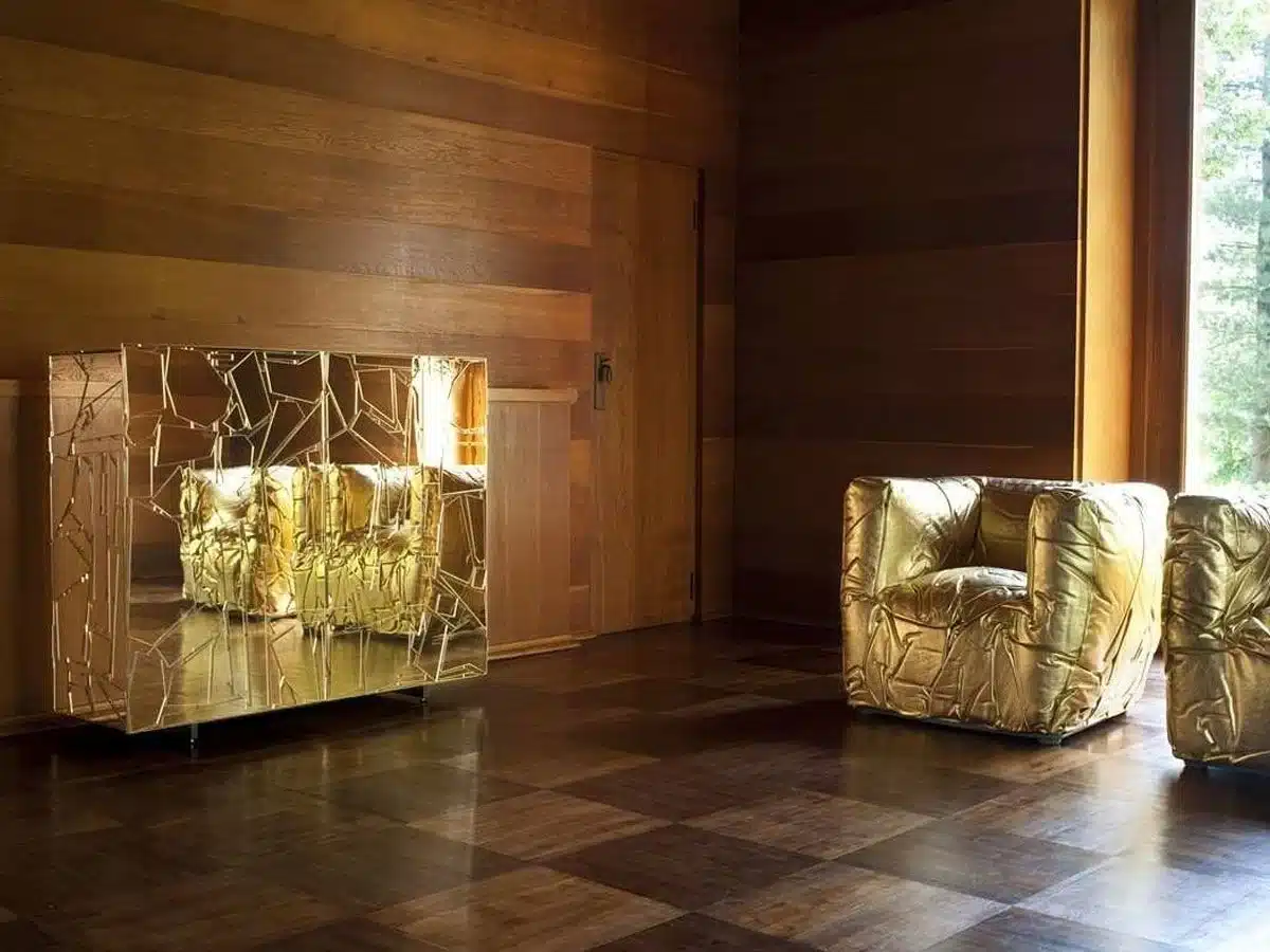 Hier zien we de Sponge-armchair in een luxe setting, gecombineerd met een spiegel die de textuur van de stoel weerspiegelt. De gouden uitvoering benadrukt het sculpturale karakter en de artistieke visie van Peter Traag. Deze presentatie laat zien hoe de stoel kan worden geïntegreerd in een ruimte die zowel modern als artistiek is.