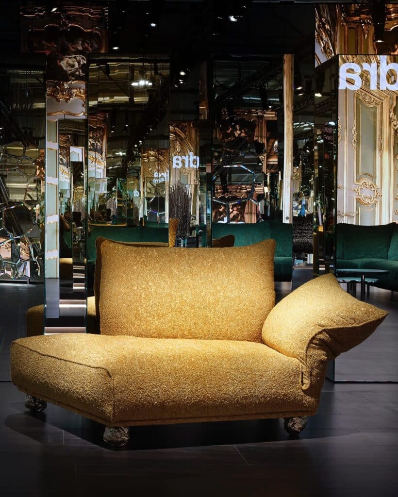 Gouden Edra-sofa gepresenteerd op Salone del Mobile 2025 – luxueus, speels design met organische vormen en barokke spiegelsetting op de achtergrond.