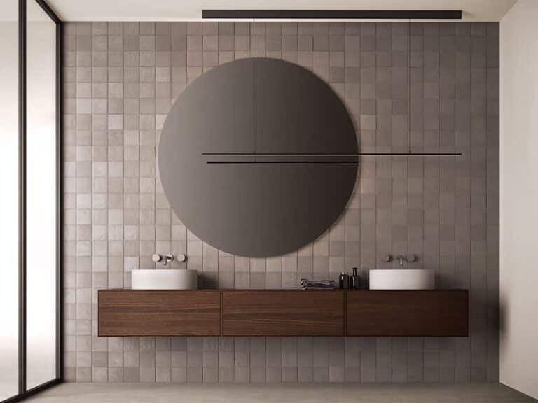 Architectonische badkameropstelling met wandgemonteerd houten wastafelmeubel, dubbele wastafels en ronde spiegel, gecombineerd met natuurstenen wandtegels in een minimalistisch interieur.