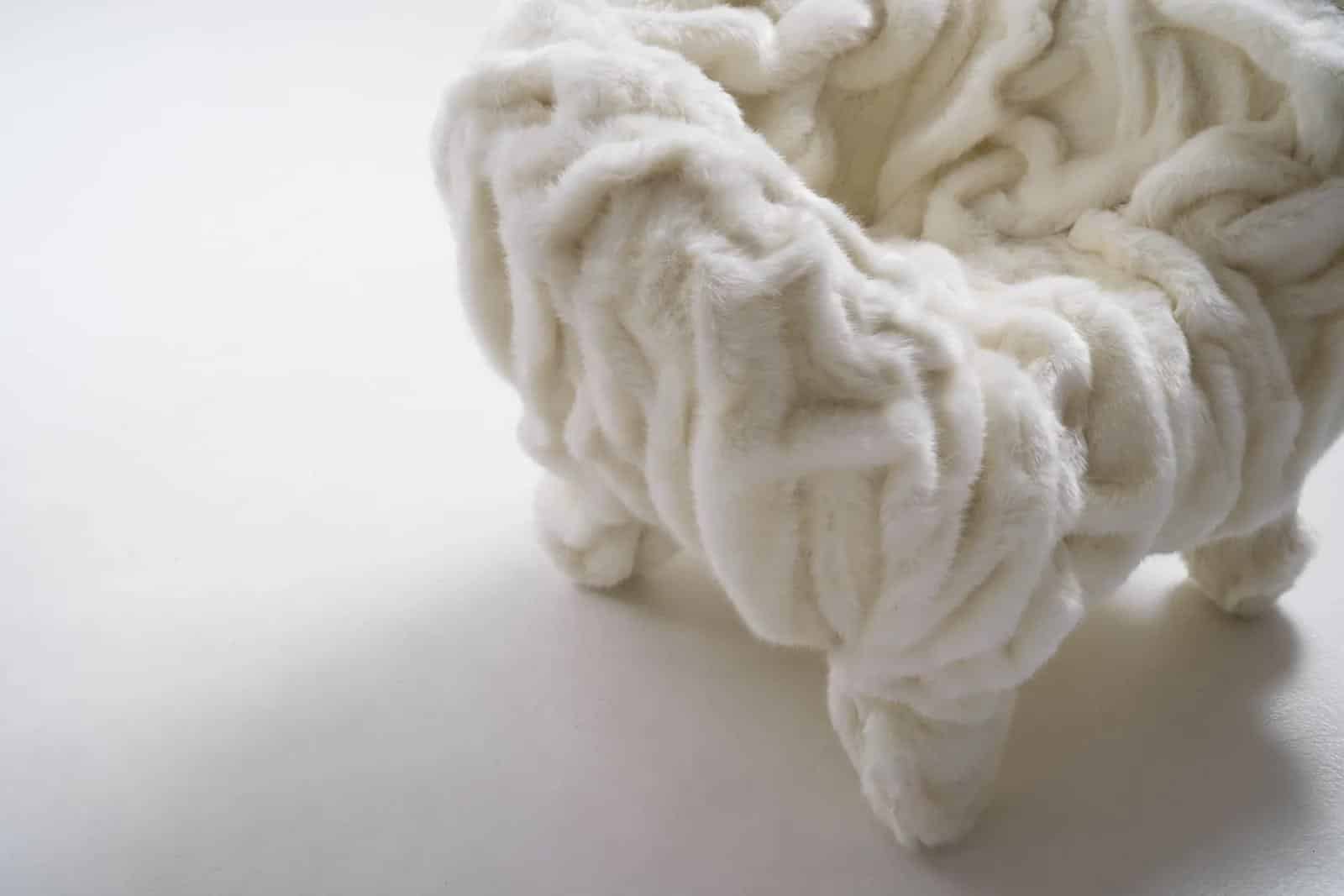 Detail van de Edra Grinza White fauteuil in bouclé bekleding, close-up van plooien, textuur en naden