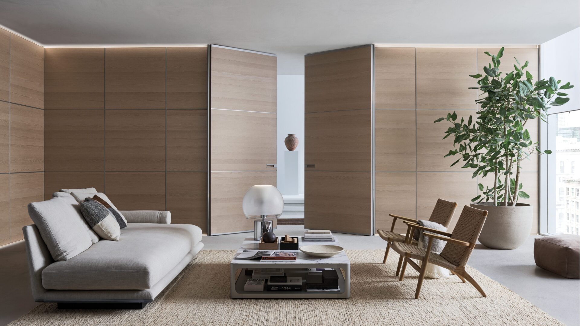 Rimadesio Air Pure taatsdeur in houtafwerking, toegepast als architectonisch binnendeursysteem in een minimalistisch interieur met zitruimte en natuurlijke materialen