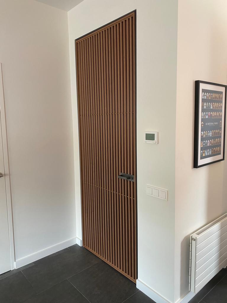 Rimadesio Sail draaideur met verticale houten lamellen toegepast als architectonische doorgang in een modern interieur
