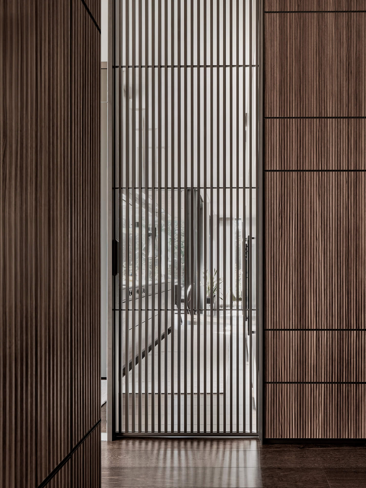 Rimadesio Sail schuifdeur met verticale aluminium profilering en glas, toegepast als doorgang binnen een maatwerkinterieur, merk Rimadesio