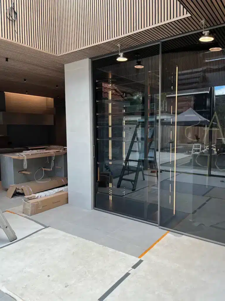Glazen wand met geïntegreerde vitrinekast op maat als onderdeel van een modern maatwerk interieur.